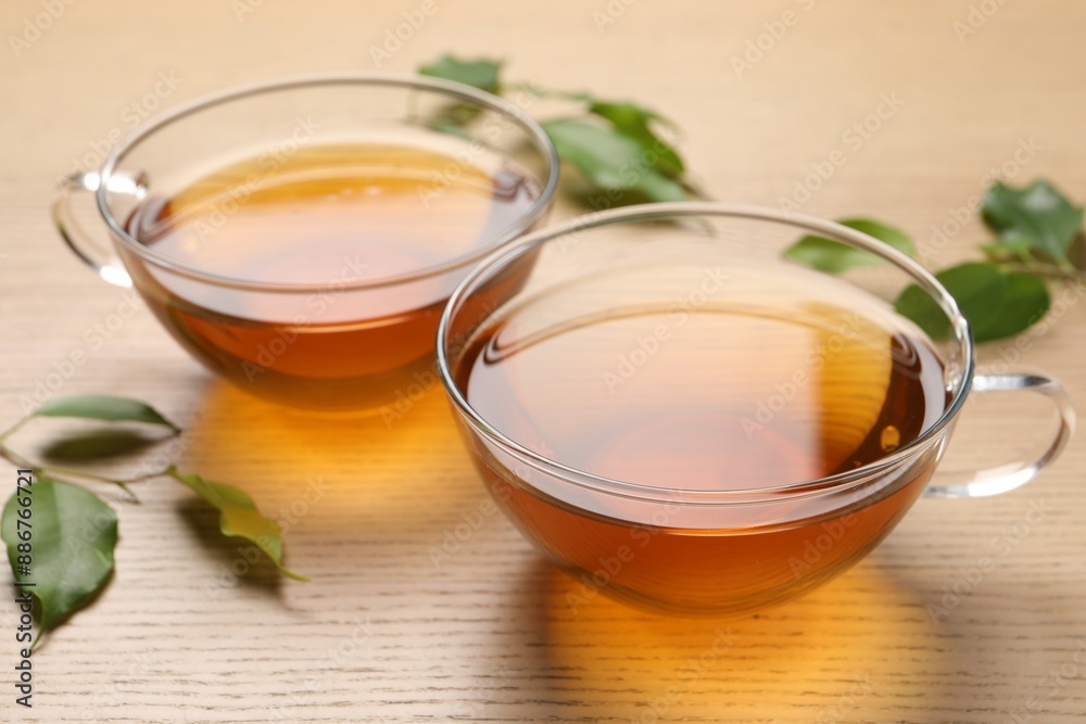 Refreshing green tea in cups and leaves on wooden table, closeup Refreshing green tea in cups and leaves on wooden table, closeup