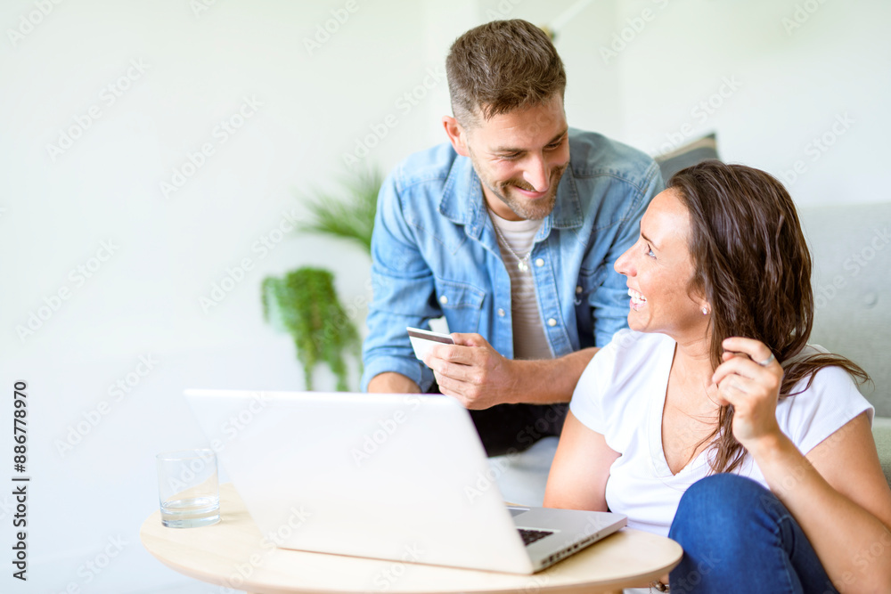bearded husband cuddling affectionate wife on computer at home. Using laptop in living room. bearded husband cuddling affectionate wife on computer at home. Using laptop in living room.