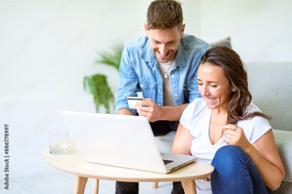 bearded husband cuddling affectionate wife on computer at home. Using laptop in living room. bearded husband cuddling affectionate wife on computer at home. Using laptop in living room.