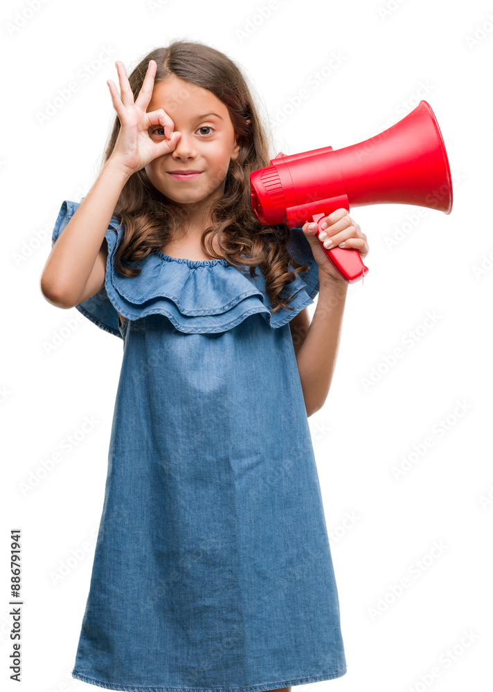 Brunette hispanic girl holding red megaphone with happy face smiling doing ok sign with hand on eye looking through fingers Brunette hispanic girl holding red megaphone with happy face smiling doing ok sign with hand on eye looking through fingers