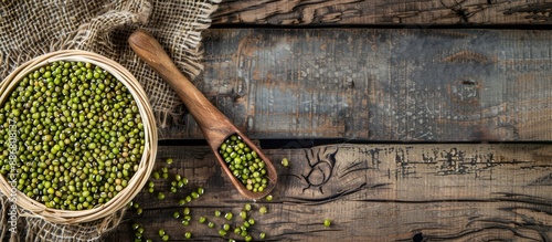 Top view of a basket containing raw mung beans and a wooden spoon on a wooden background, with copy space image. photo