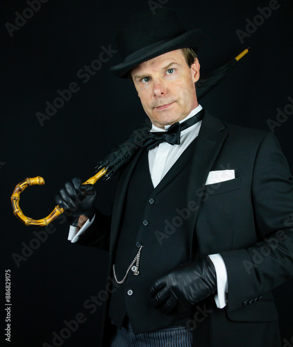Elegant Vintage Gentleman in Dark Suit and Bowler Hat Holding Umbrella. Wealthy Upper Class English Snob.