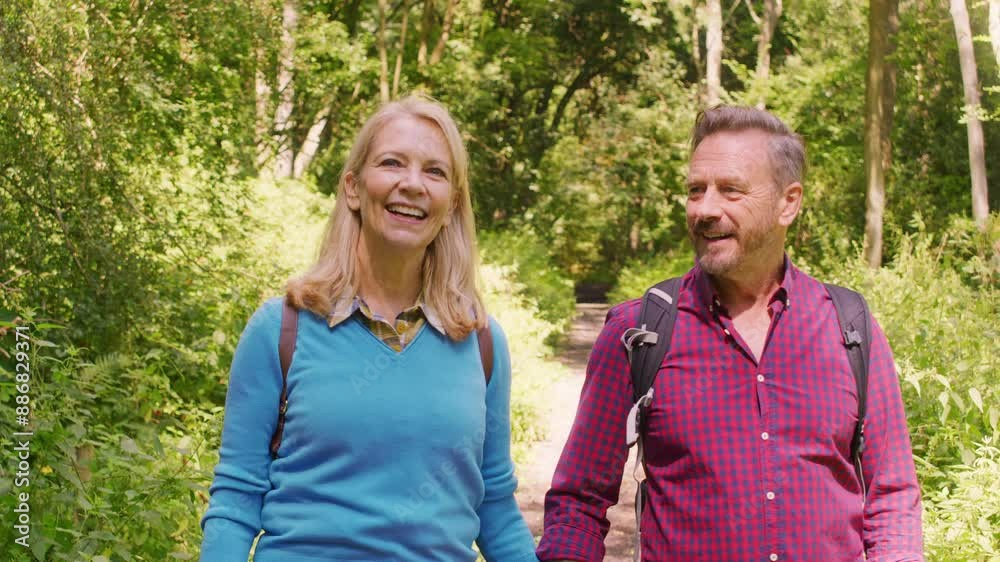 Loving mature couple walking along path through trees on hike holding hands - shot in slow motion