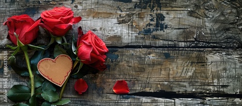 Red roses and a heart-shaped card placed on weathered wood with copy space image for your message.