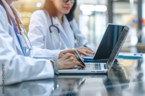 Two Doctors Working on Laptops in a Hospital Setting © arttools