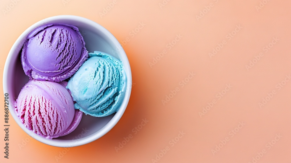 A bowl containing three vibrant ice cream scoops against a white background on a pink-orange backdrop, viewed from above A bowl containing three vibrant ice cream scoops against a white background on a pink-orange backdrop, viewed from above