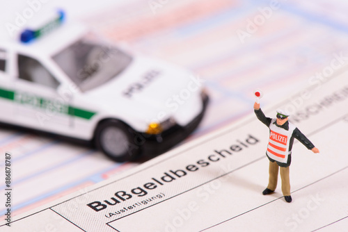 Photos Ein Modell-Polizist steht mit einem Modell-Polizeiauto auf einem Bußgeldbescheid