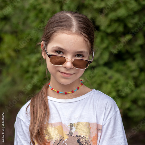 Fashionable little girl in sunglasses looking at the camera