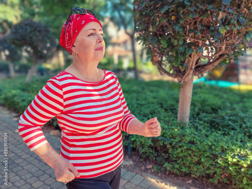 In the morning park, a bald woman wearing a red bandana runs energetically, using her chemotherapy-free days to stay active and combat cancer.