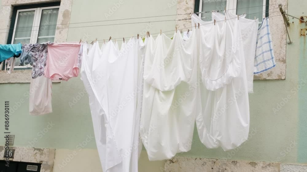 Drying clothes outdoors. Authentic video of bed sheets being dried on rope hanging by the window. Traditions of Portugal