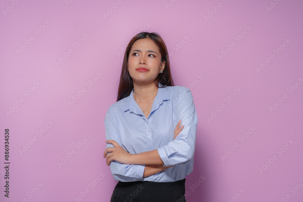 Young asian businesswoman folding her arms with an annoyed expression on a pink background, conveying a sense of frustration or disagreement Young asian businesswoman folding her arms with an annoyed expression on a pink background, conveying a sense of frustration or disagreement