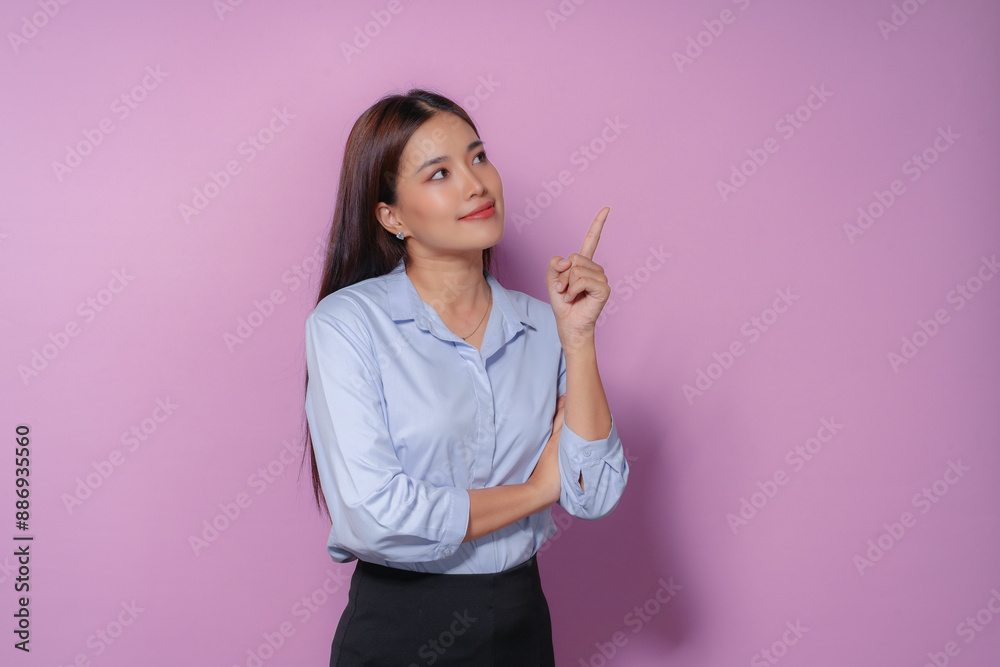 Confident young asian businesswoman pointing up on purple background, ideal for career success concepts Confident young asian businesswoman pointing up on purple background, ideal for career success concepts