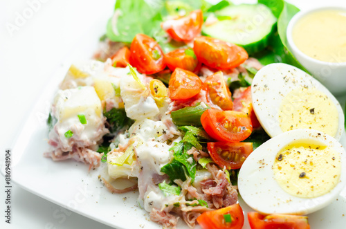 A plate of food with a salad, eggs, and a sauce