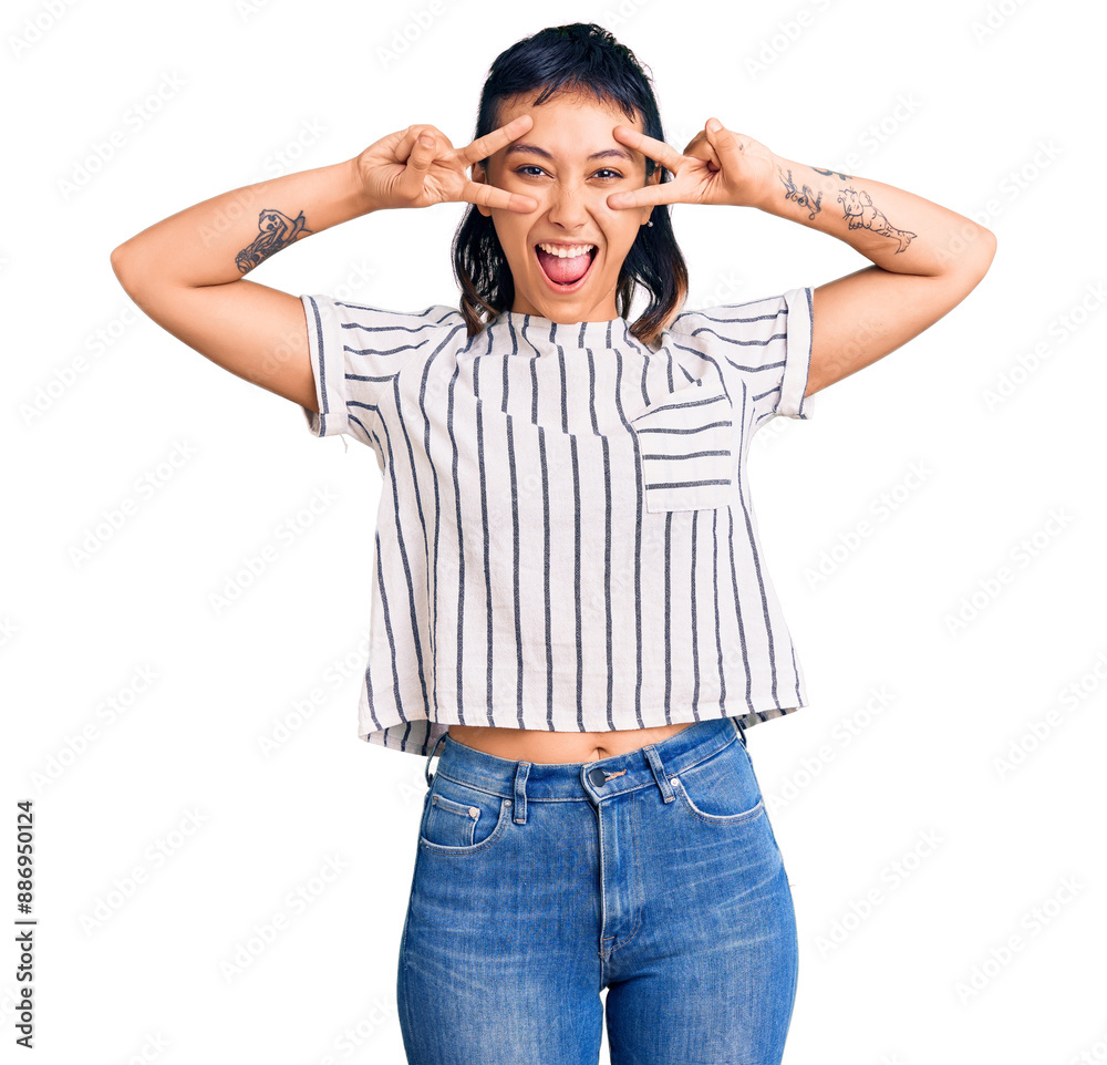 Young woman wearing casual clothes doing peace symbol with fingers over face, smiling cheerful showing victory Young woman wearing casual clothes doing peace symbol with fingers over face, smiling cheerful showing victory