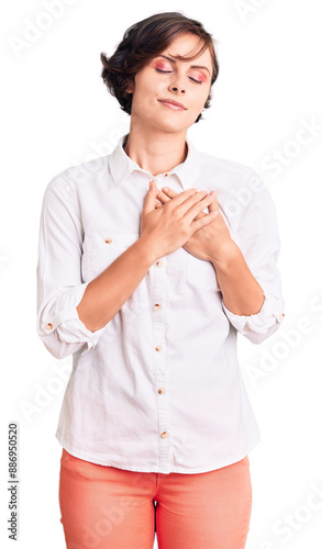 Beautiful young woman with short hair wearing elegant white shirt smiling with hands on chest with closed eyes and grateful gesture on face. health concept.