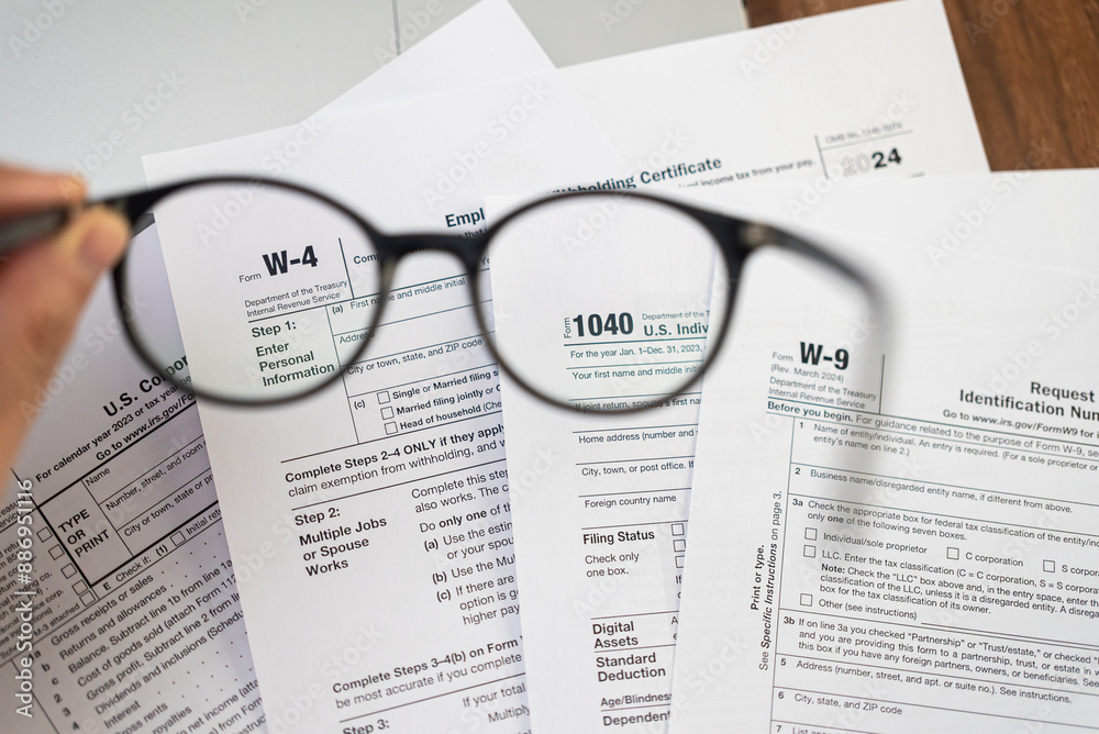 Male hand holds glasses above different tax forms mandatory for taxpayers to report annual income and financial information to avoid penalties from government Male hand holds glasses above different tax forms mandatory for taxpayers to report annual income and financial information to avoid penalties from government