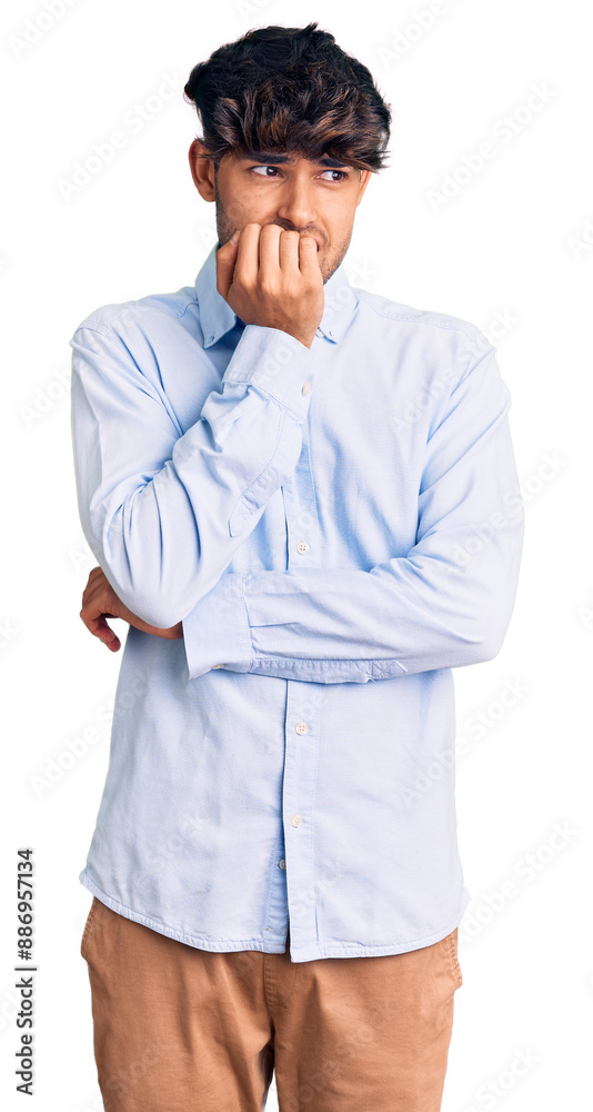 Young hispanic man wearing casual shirt looking stressed and nervous with hands on mouth biting nails. anxiety problem. Young hispanic man wearing casual shirt looking stressed and nervous with hands on mouth biting nails. anxiety problem.