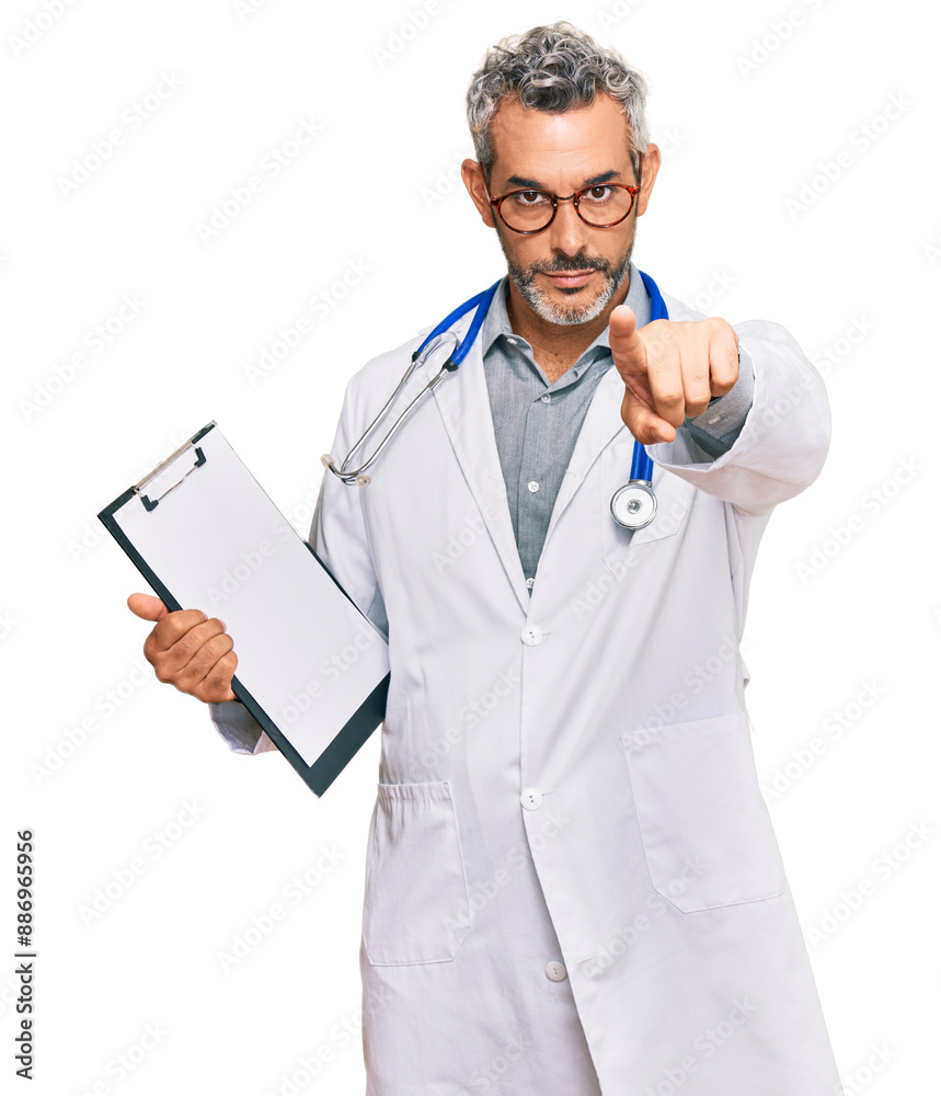 Middle age grey-haired man wearing doctor stethoscope holding clipboard pointing with finger to the camera and to you, confident gesture looking serious Middle age grey-haired man wearing doctor stethoscope holding clipboard pointing with finger to the camera and to you, confident gesture looking serious