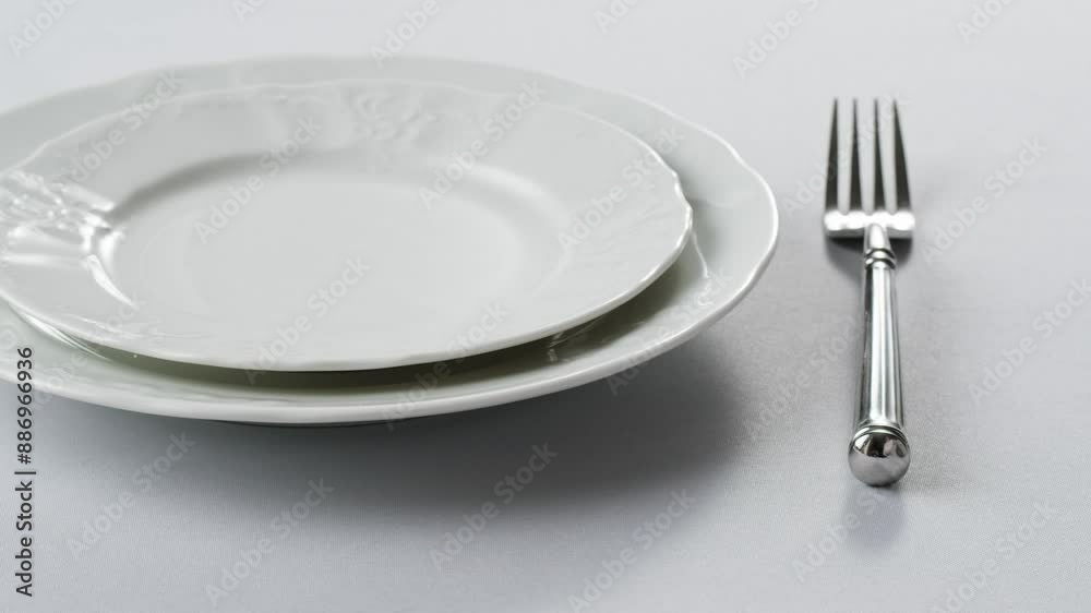 Elegant table setting with white tableware plates, cutlery, and glassware for a classy dining, fancy expensive restaurant dinner Elegant table setting with white tableware plates, cutlery, and glassware for a classy dining, fancy expensive restaurant dinner