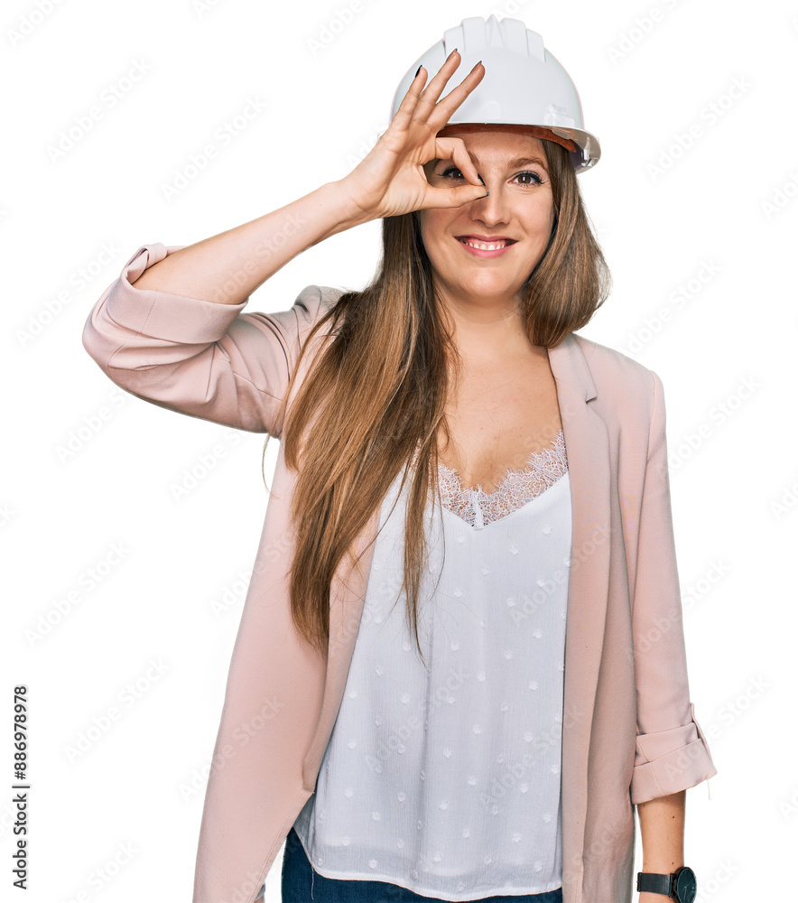Young blonde woman wearing architect hardhat smiling happy doing ok sign with hand on eye looking through fingers Young blonde woman wearing architect hardhat smiling happy doing ok sign with hand on eye looking through fingers