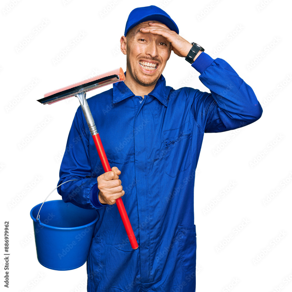 © Krakenimages.com - Bald man with beard wearing glass cleaner uniform and squeegee stressed and frustrated with hand on head, surprised and angry face
