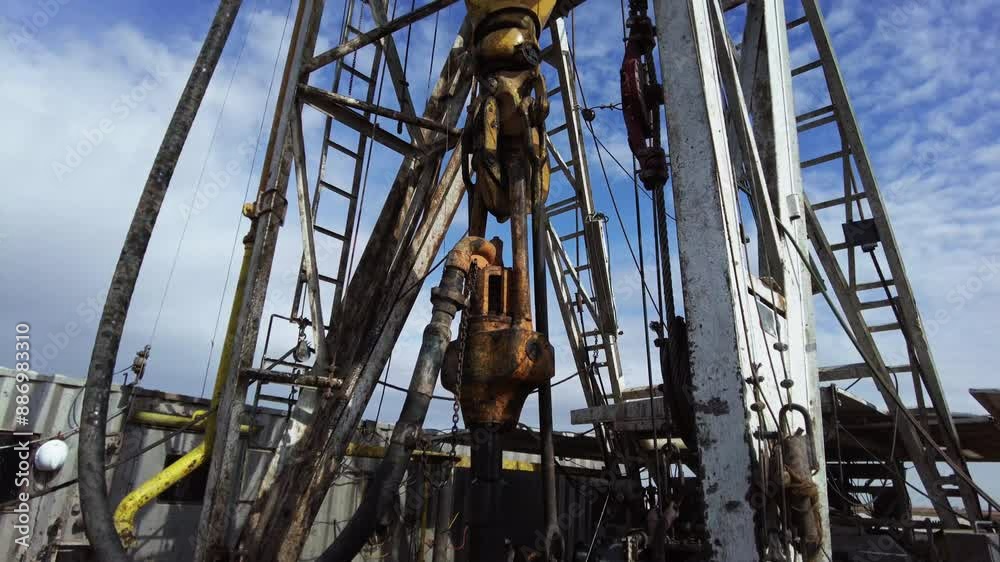 Drilling natural resources at the site for oil production. High metal derrick with equipment working. Low angle view. Drilling natural resources at the site for oil production. High metal derrick with equipment working. Low angle view.