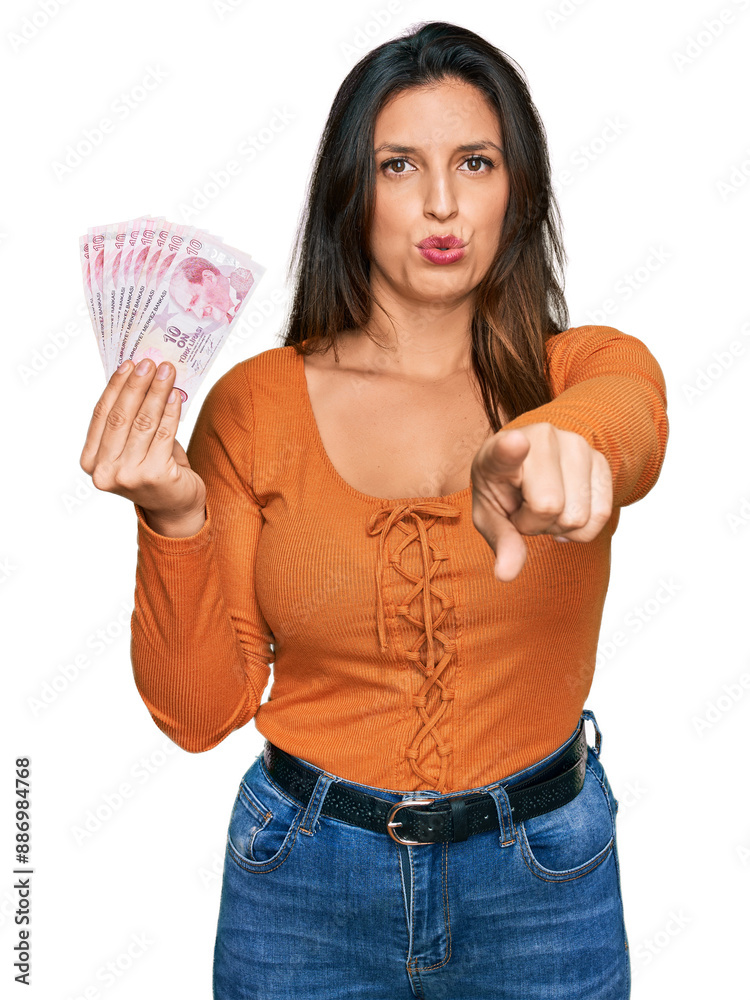 Beautiful hispanic woman holding 50 turkish lira banknotes pointing with finger to the camera and to you, confident gesture looking serious Beautiful hispanic woman holding 50 turkish lira banknotes pointing with finger to the camera and to you, confident gesture looking serious