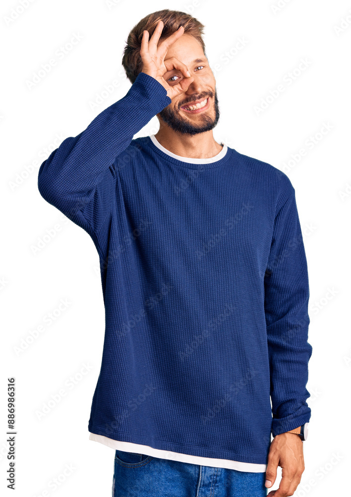 Handsome blond man with beard wearing casual sweater doing ok gesture with hand smiling, eye looking through fingers with happy face. Handsome blond man with beard wearing casual sweater doing ok gesture with hand smiling, eye looking through fingers with happy face.