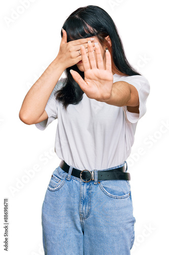 Young hispanic girl wearing casual clothes covering eyes with hands and doing stop gesture with sad and fear expression. embarrassed and negative concept.