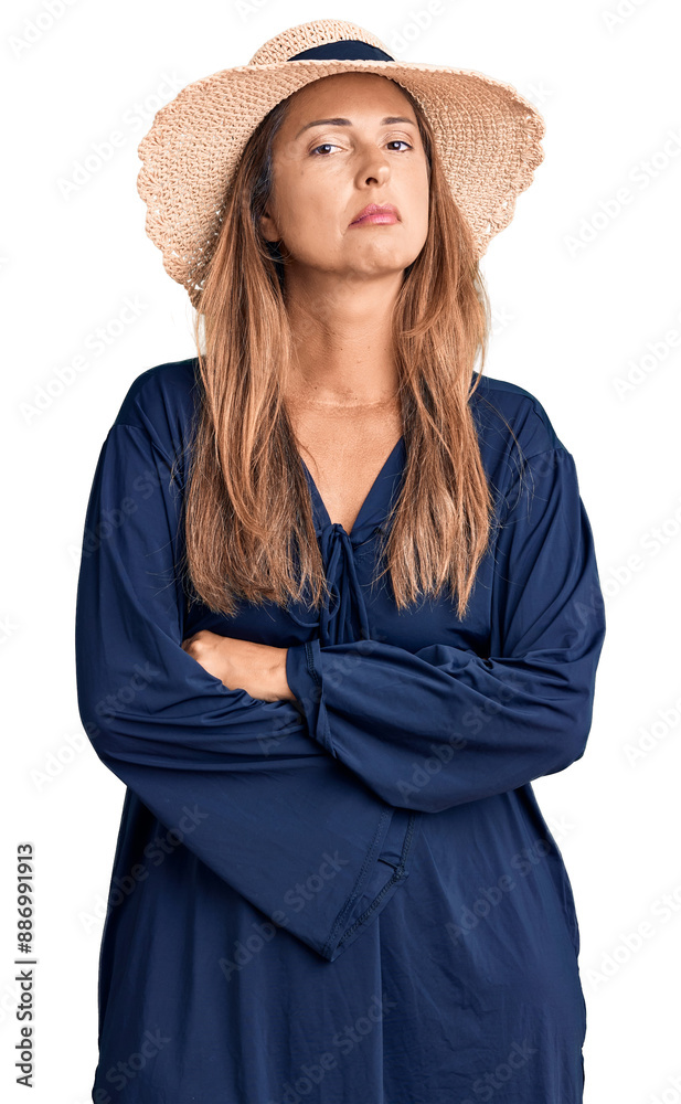 Fototapeta premium Middle age hispanic woman wearing summer hat relaxed with serious expression on face. simple and natural looking at the camera.