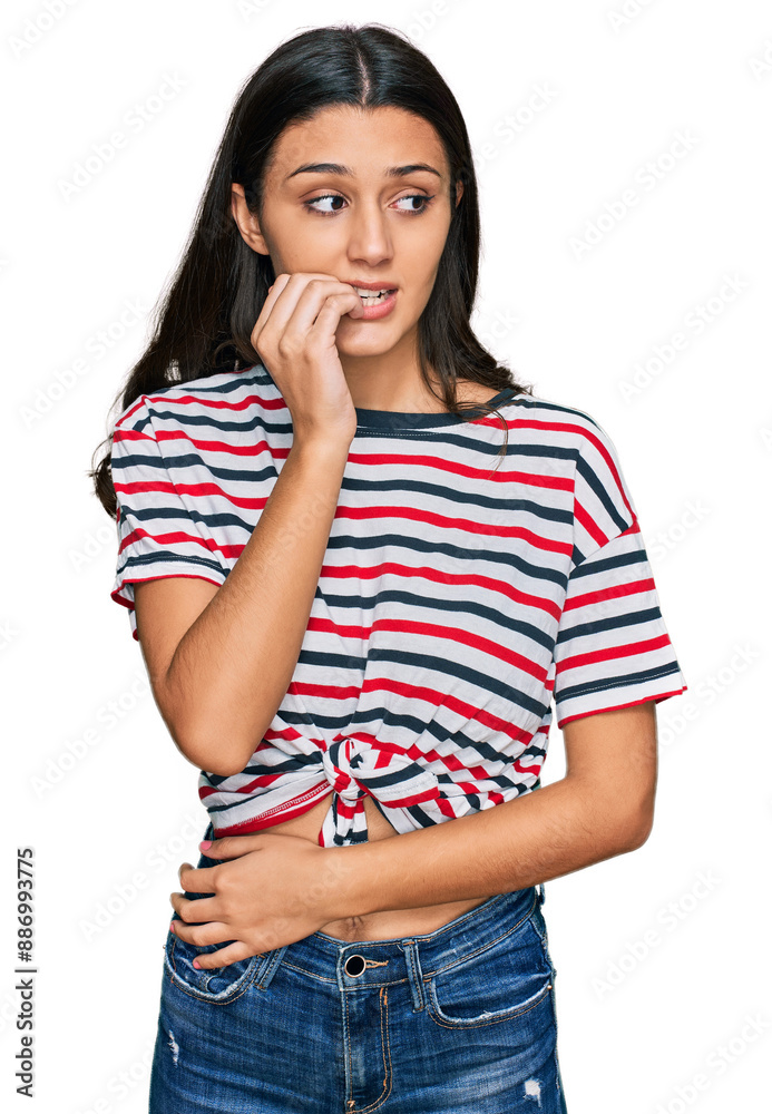 Young hispanic girl wearing casual clothes looking stressed and nervous with hands on mouth biting nails. anxiety problem. Young hispanic girl wearing casual clothes looking stressed and nervous with hands on mouth biting nails. anxiety problem.