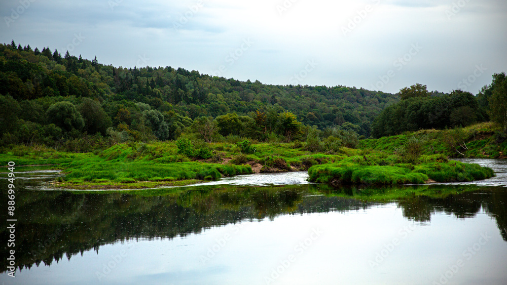 Tranquil river landscape with lush green forest and calm waters, creating a serene environment Tranquil river landscape with lush green forest and calm waters, creating a serene environment