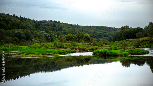 Tranquil river landscape with lush green forest and calm waters, creating a serene environment