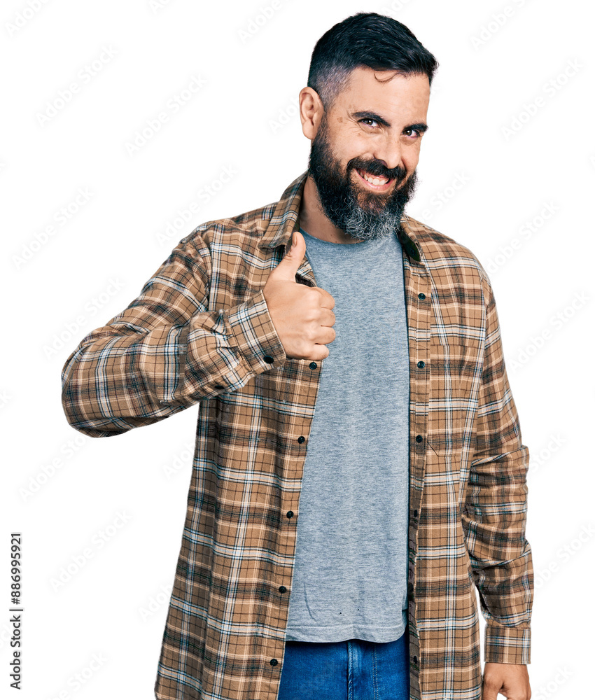 Hispanic man with beard wearing casual shirt doing happy thumbs up gesture with hand. approving expression looking at the camera showing success.