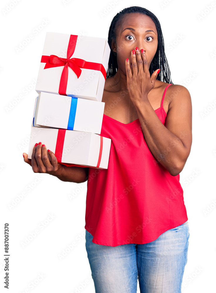 Young african american woman holding gift covering mouth with hand, shocked and afraid for mistake. surprised expression Young african american woman holding gift covering mouth with hand, shocked and afraid for mistake. surprised expression