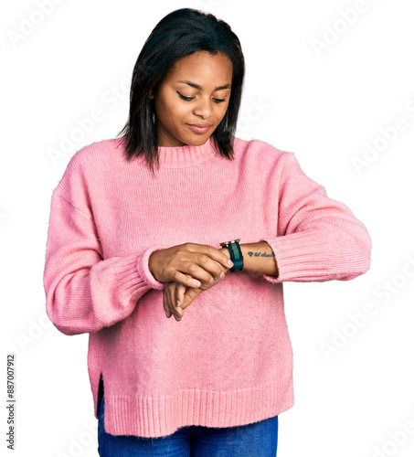 Beautiful hispanic woman wearing casual winter sweater checking the time on wrist watch, relaxed and confident
