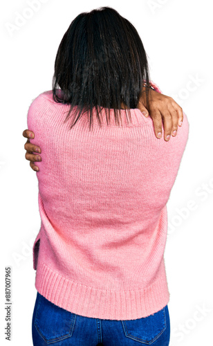 Beautiful hispanic woman wearing casual winter sweater hugging oneself happy and positive from backwards. self love and self care