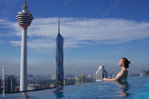 Photography Young woman in a roof top swimming pool with beautiful city view