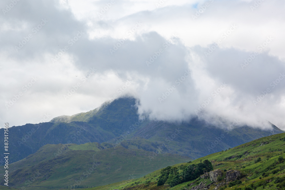 View of Crib Goch from the Llynnau Mymbyr lake by the small small town of Capel Curig on a cloudy day, Image shows a beautiful scenic view of the mountains of Snowdonia with cloud covering the sumit View of Crib Goch from the Llynnau Mymbyr lake by the small small town of Capel Curig on a cloudy day, Image shows a beautiful scenic view of the mountains of Snowdonia with cloud covering the sumit