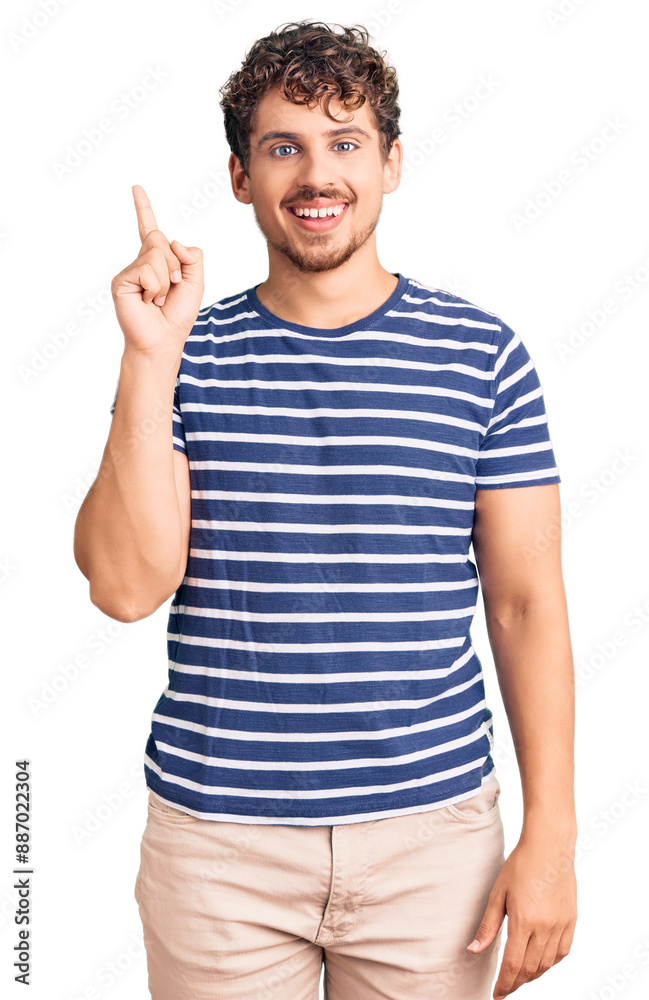 Young handsome man with curly hair wearing casual clothes showing and pointing up with finger number one while smiling confident and happy. Young handsome man with curly hair wearing casual clothes showing and pointing up with finger number one while smiling confident and happy.