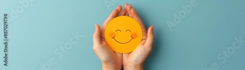 Hands holding a yellow smiley face on a blue background.