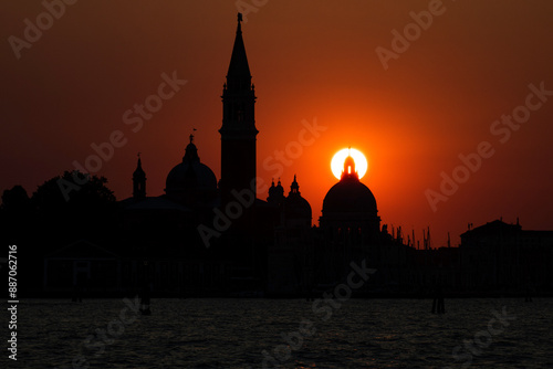 A beautiful silhouette shot of San Giorgio Maggiore Church in Venice, Italy with the setting sun perfectly positioned behind the church dome. photo