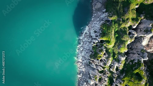 On the shores of Lake Mont Cenis between France and Italy, 4K drone video between the lake and the rock, vertical view