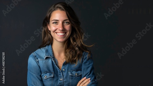 Smiling, happy Caucasian young woman, in a denim shirt, looking at the camera with arms crossed