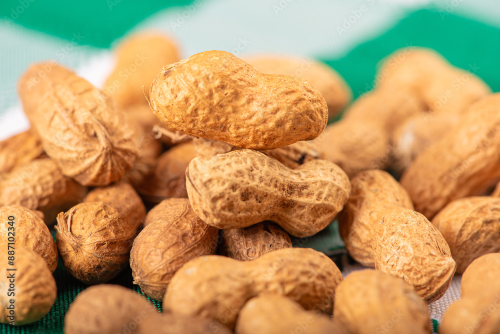 Peanuts, portion of peanuts in shell on a green and white checkered tablecloth. Selective focus. Peanuts, portion of peanuts in shell on a green and white checkered tablecloth. Selective focus.