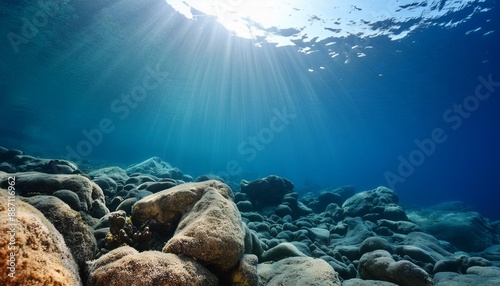 dark blue water of a deep ocean with sun rays reaching the rocky seabed beautiful underwater landscape