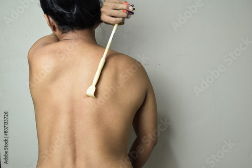 Back of man using stick to scratch the back help scracth the skin itching from dermatitis photo