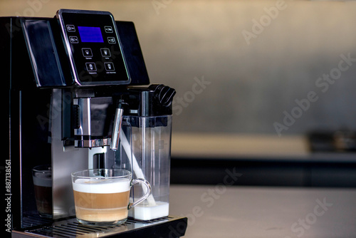 Modern coffee machine with glass cup of latte in kitchen