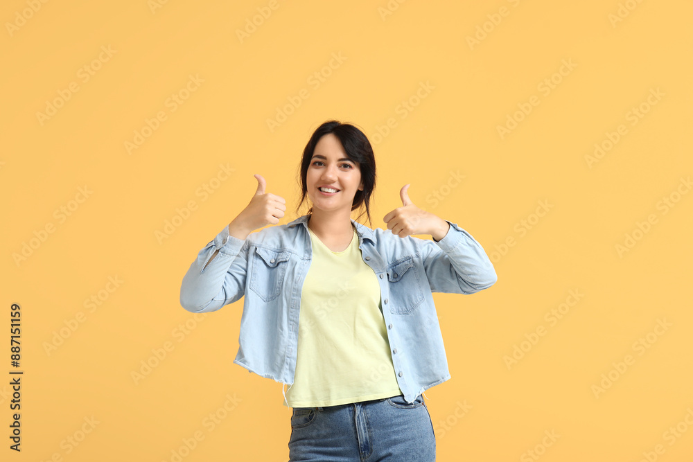 Portrait of happy young brunette showing thumb-up on yellow background Portrait of happy young brunette showing thumb-up on yellow background