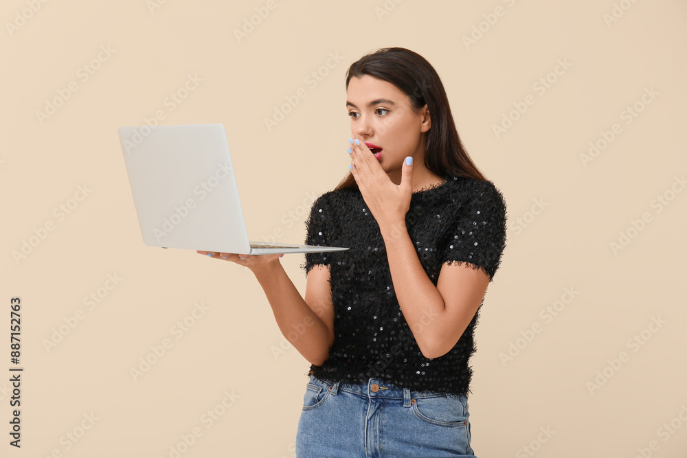 Beautiful young shocked woman with laptop on beige background Beautiful young shocked woman with laptop on beige background